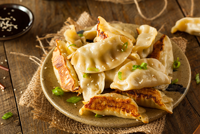 Plate of dumplings and bowls of sauce on a wooden table
