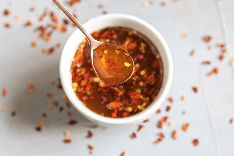 Une petite cuillère dans un ramequin de sirop d'érable et de flocons de chili.